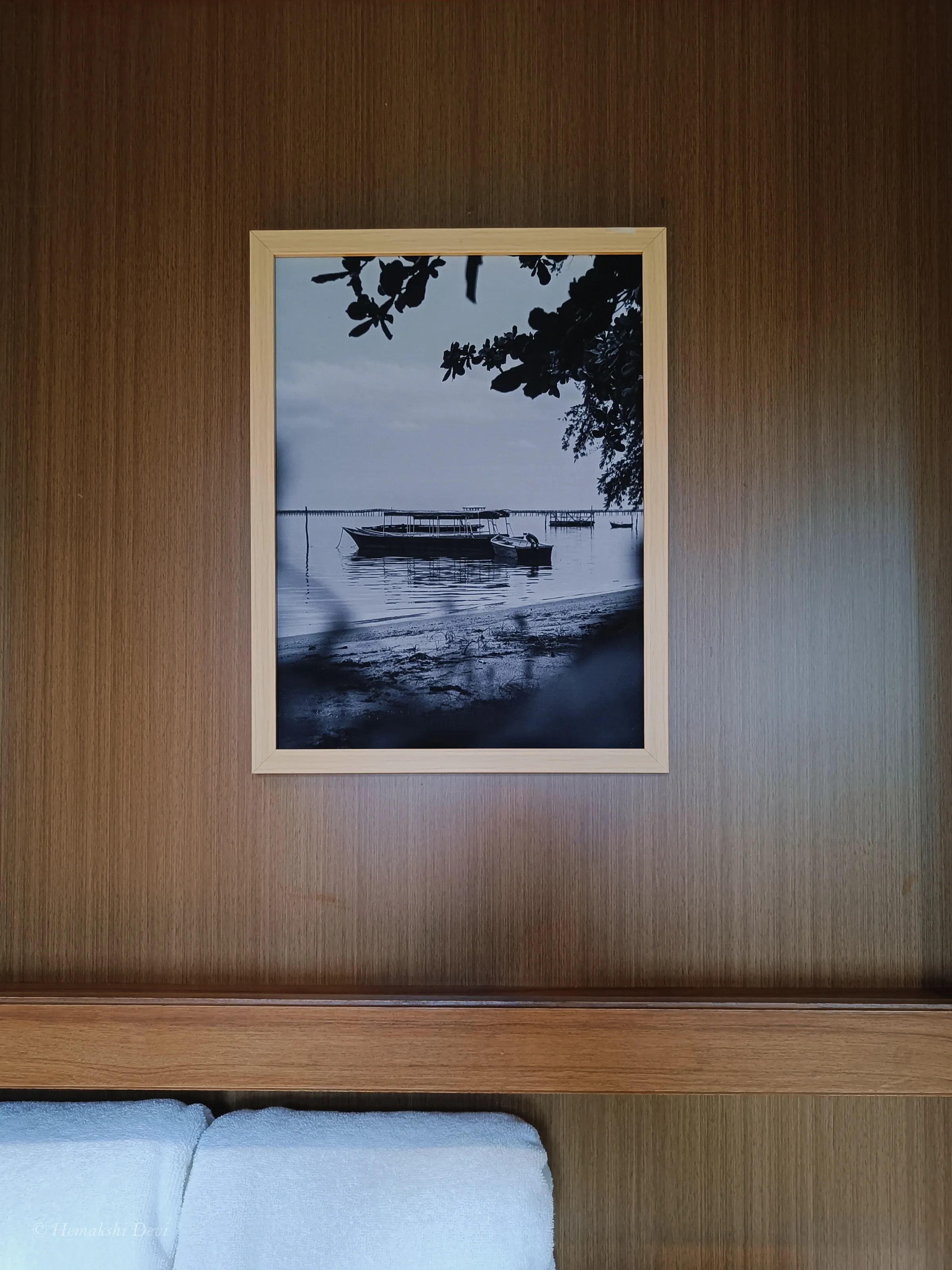 Framed monochrome digital photograph of a boat on the water, in a guest bathroom